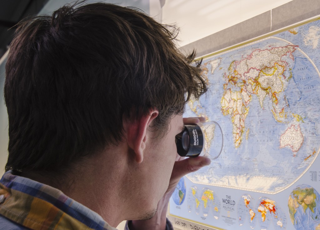 A man uses a loupe to take a close look at the details in this HD C-Print® of a map on a lightbox.