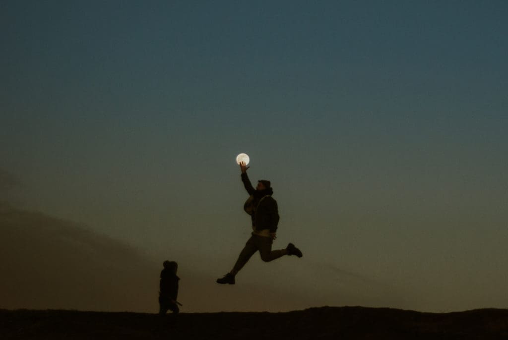 photographer reaching for the moon at dusk