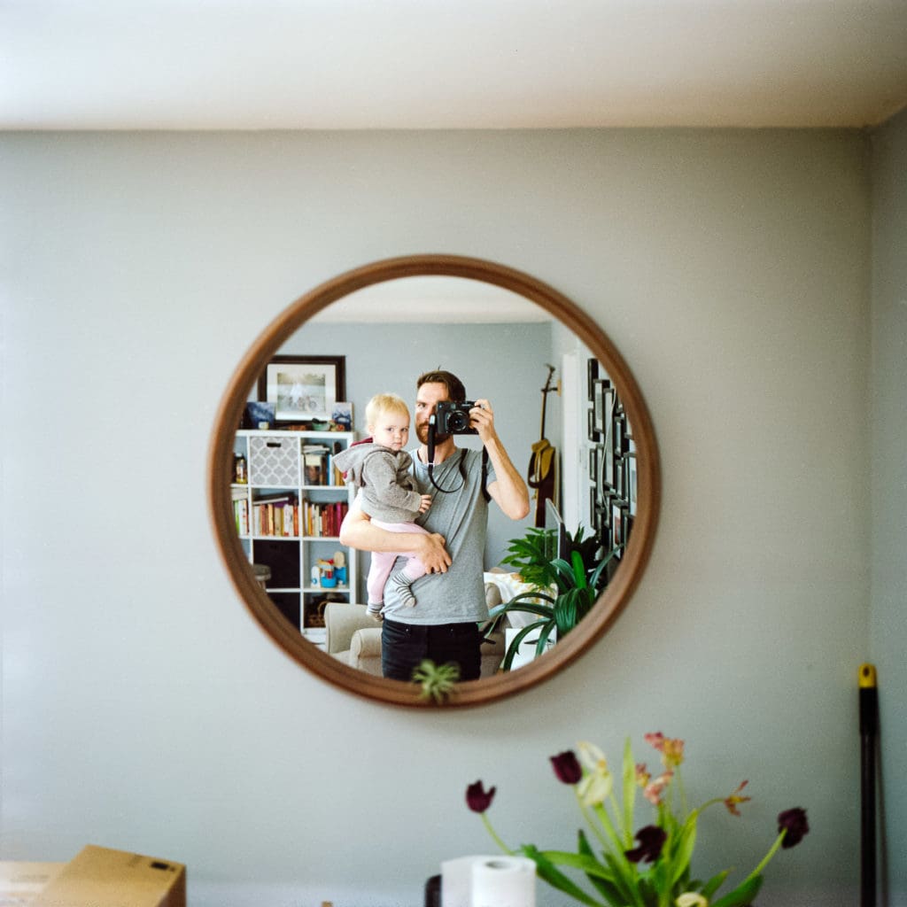 An image of Joe Tobiason holding his young daughter photographed with a film camera