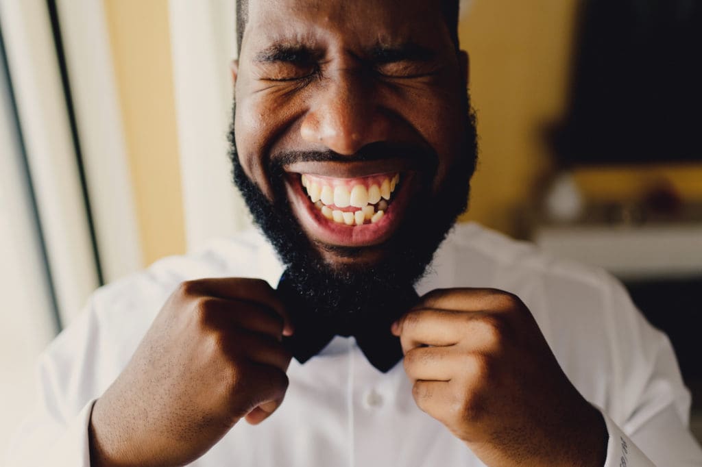 An Image of a groom getting ready and fixing his bow tie.