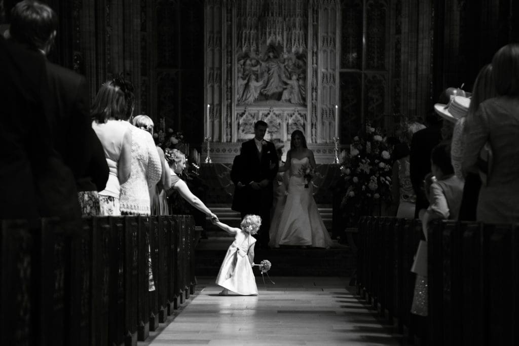 flower girl in wedding aisle at church black and white photography by martin dabek