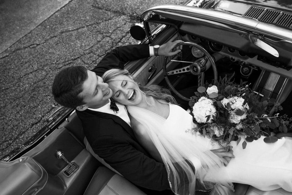 The bride and groom pose for a great photo op in groom's vintage car.