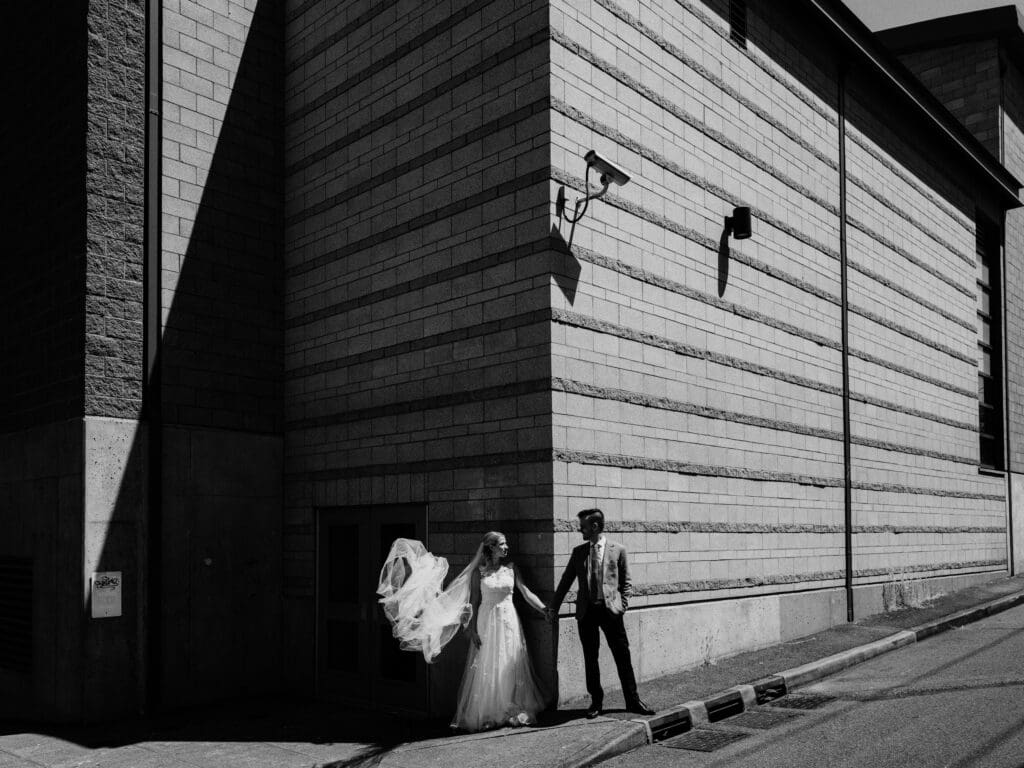 a portrait based on light and composition, as bride and groom meet at a building's intersection.