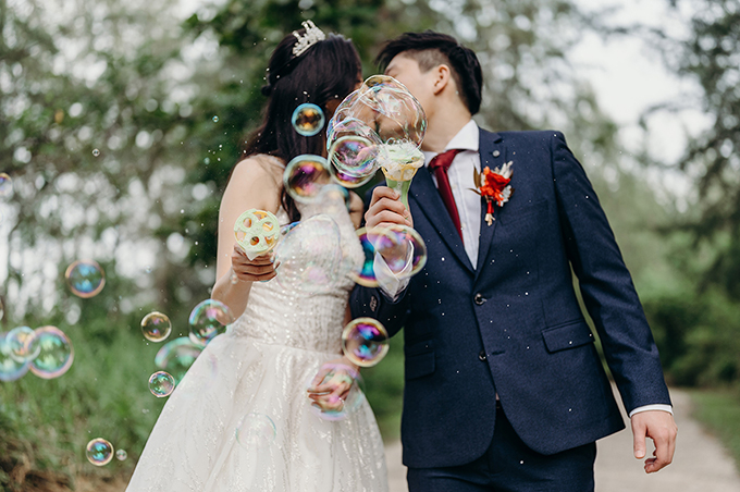 a bride and groom kiss behind bubbles.