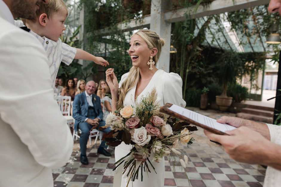 Bride with son reaching out to her at wedding.