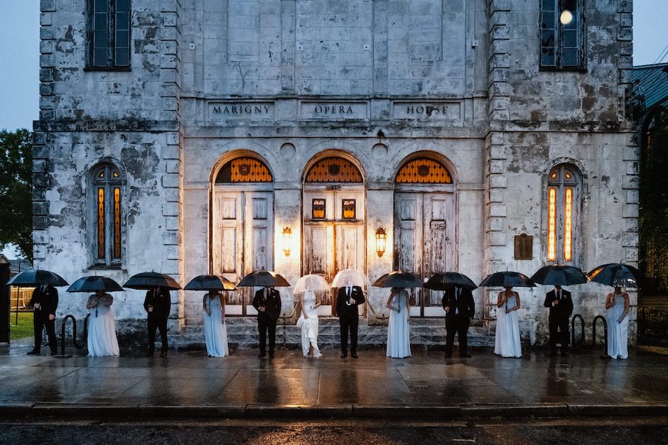 wedding party with umbrellas in rain in front of opera house for distinctive photo looks.