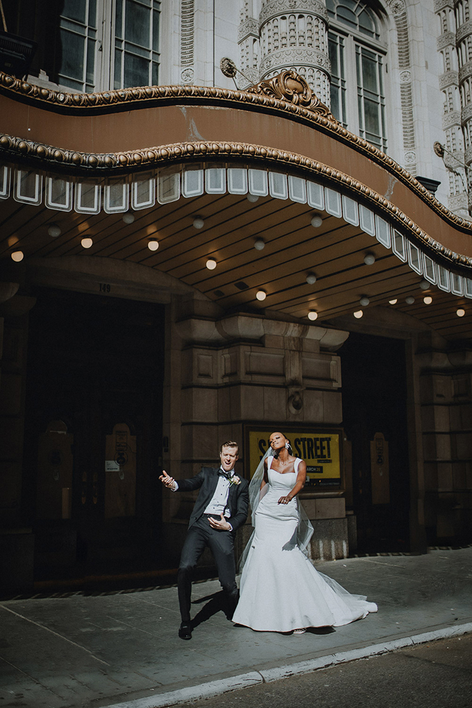 newlywed broadway actors dance in front of new york city theater district