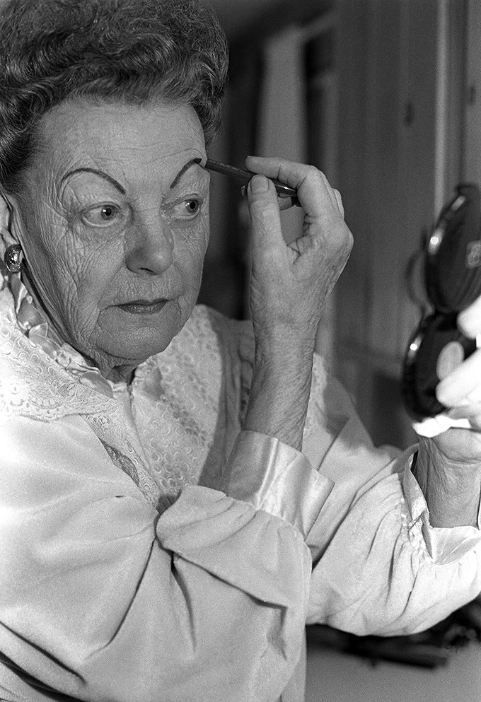 black and white portrait of kay olson putting on eyebrows with makeup