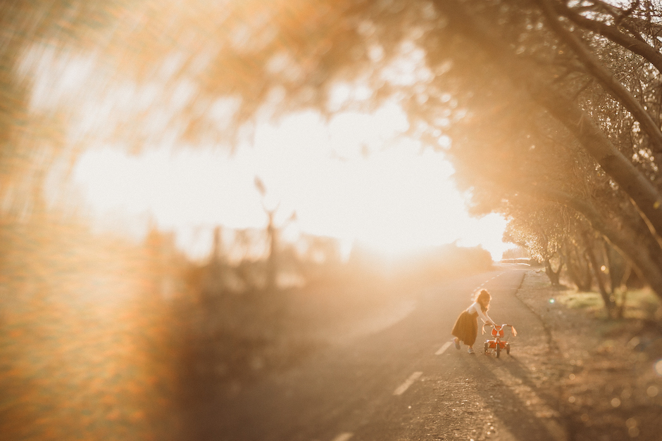 eye-catching lens haze as little girl walks her bike down road.