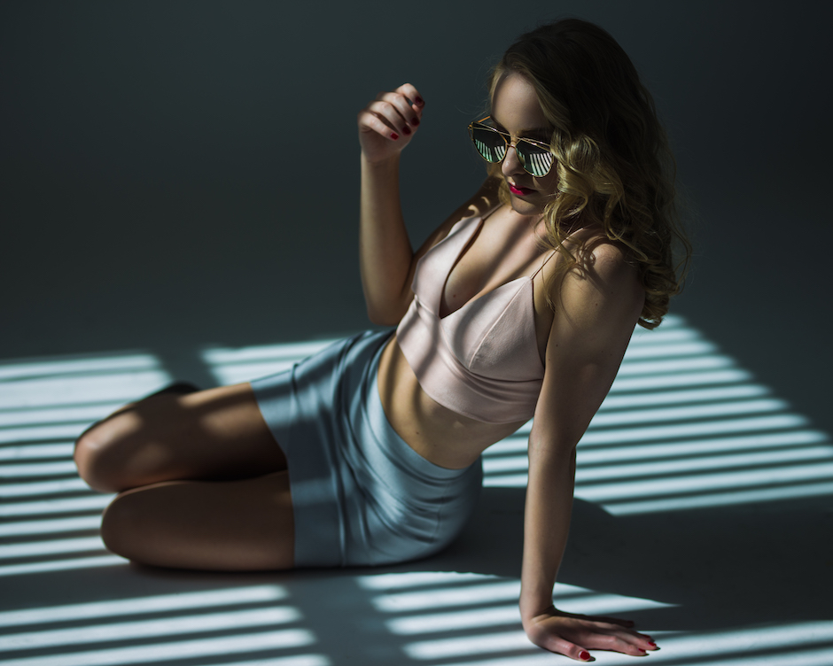 fashion shot of model with striking outfit, sunglasses , unique photo lighting.