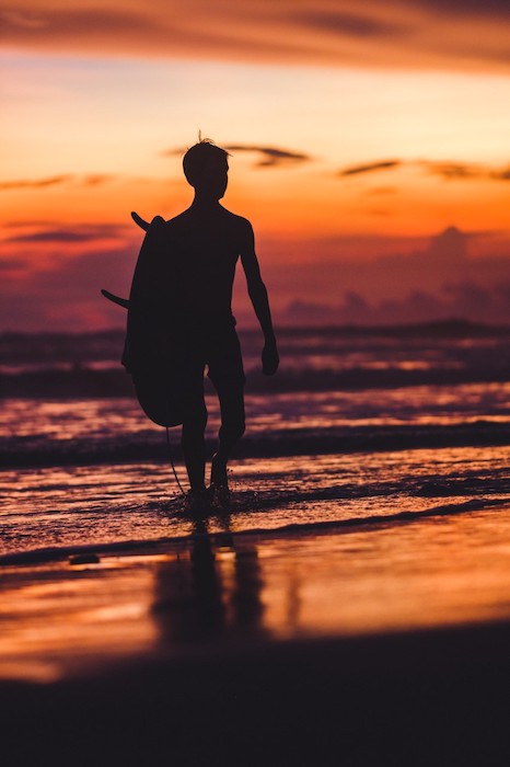 portrait of boy with surfboard on beach.
