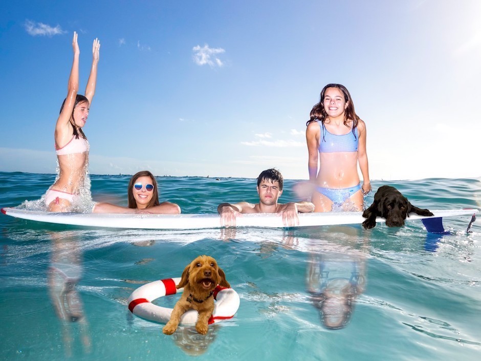 Family on surfboard in ocean.