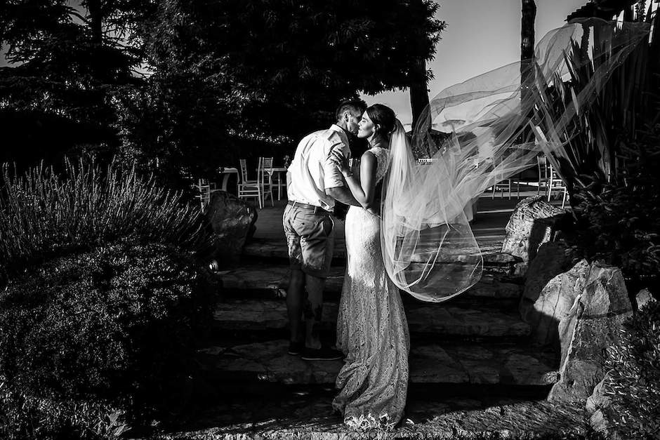 bide and groom in garden with movement of veil in air.