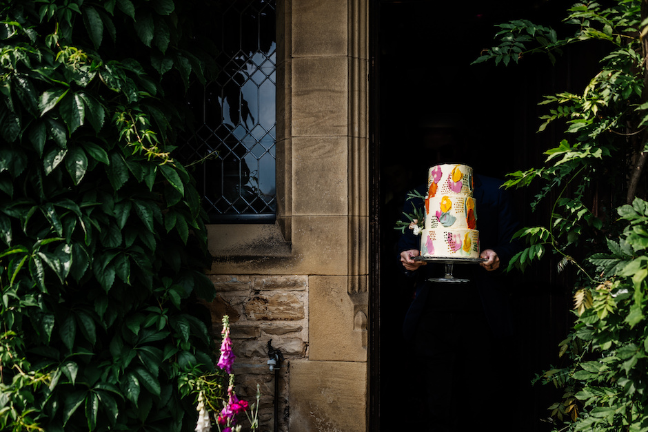wedding cake with just hands showing in the shadows.