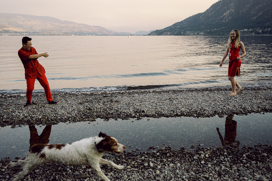 elopement couple in front of lake with dog in foreground.